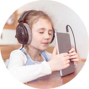 Young girl listening to music through headphones using a tablet device.
