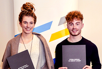 a young woman and a young man smiling and holding certificates