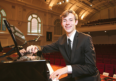 young man sitting at a piano smiling