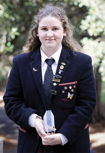A girl wearing a school uniform holding a trophy