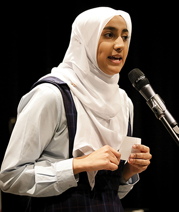 A girl wearing a headscarf speaking into a microphone