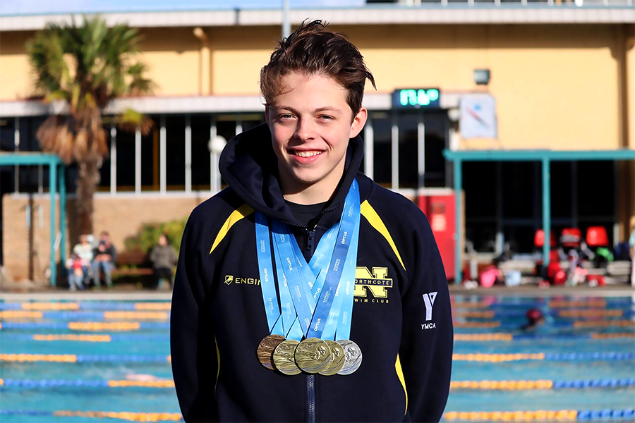 A boy wearing a tracksuit with medals around his neck