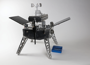 a model of a warning system made of metal an antenna on top and four legs