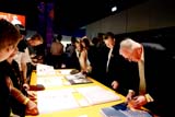 People looking through booklets displayed in an indoor exhibition space