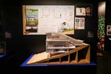 An architectural model on display, behind which are concept boards and branding.